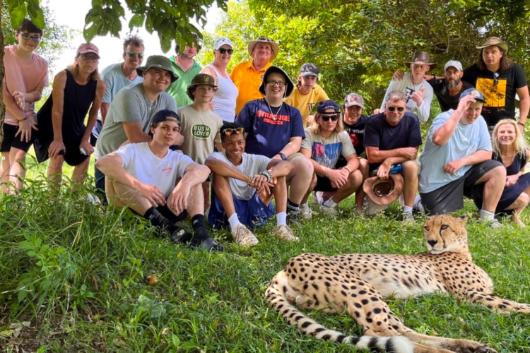 Trinity-Pawling students sitting in the grass with a cheetah in South Africa
